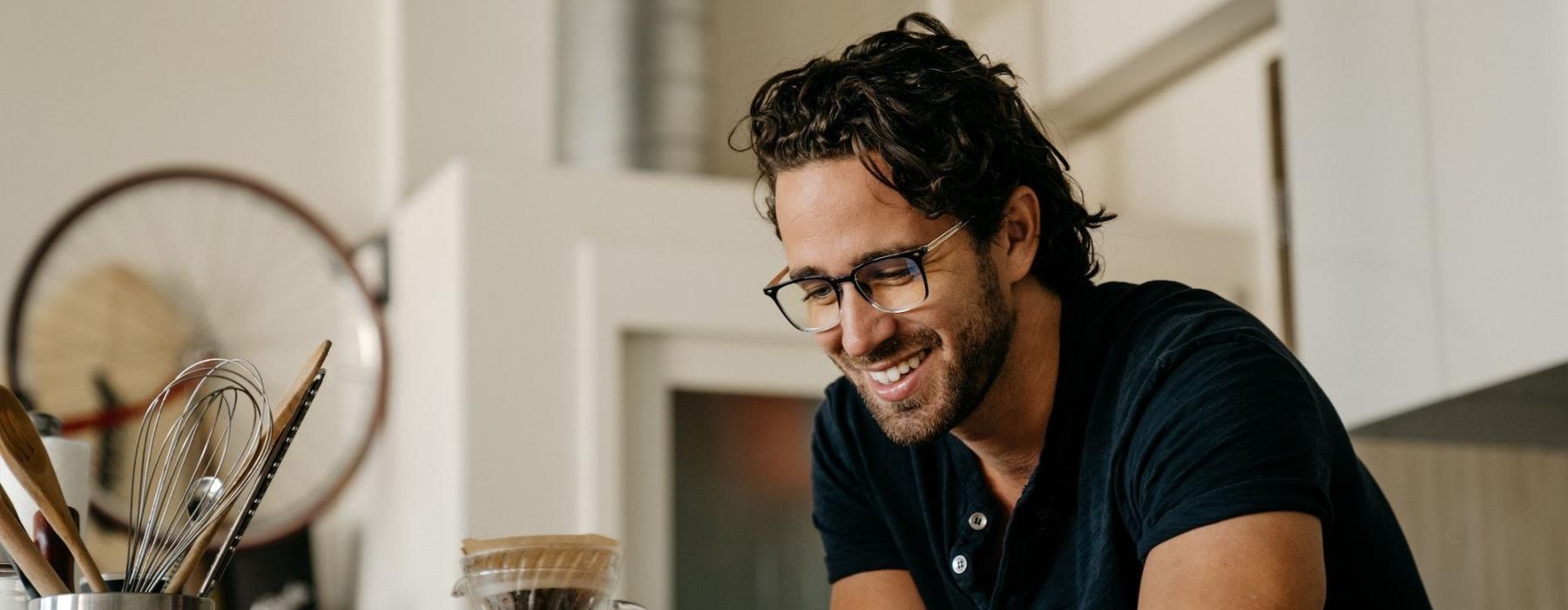 Man with glasses smiling and holding a phone