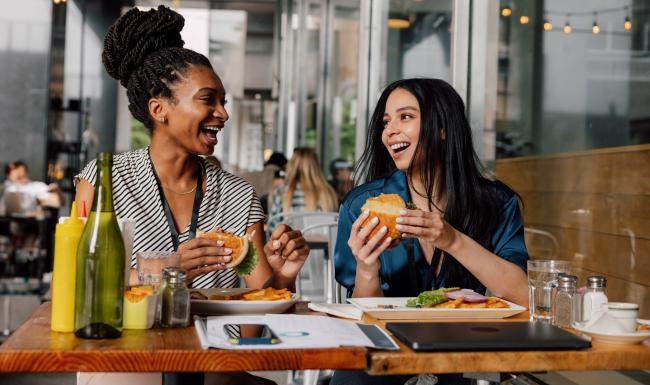 A couple of women eating burgers at a restaurant